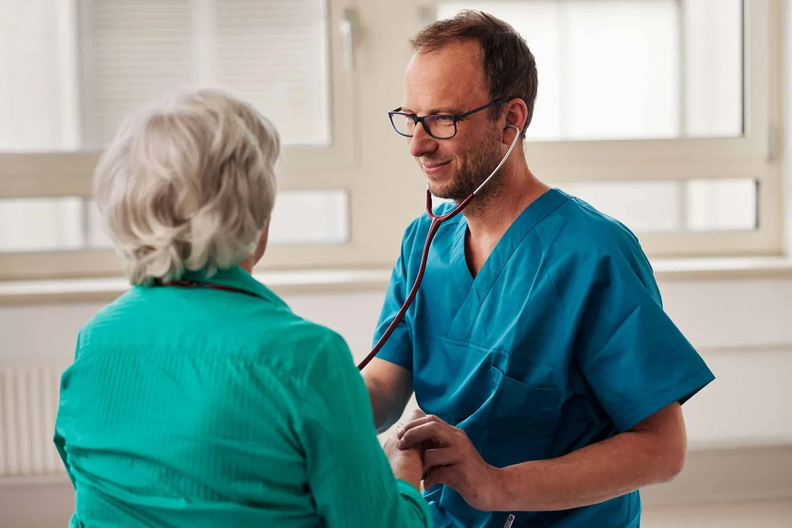 Arzt hört eine ältere Patientin mit dem Stethoskop ab