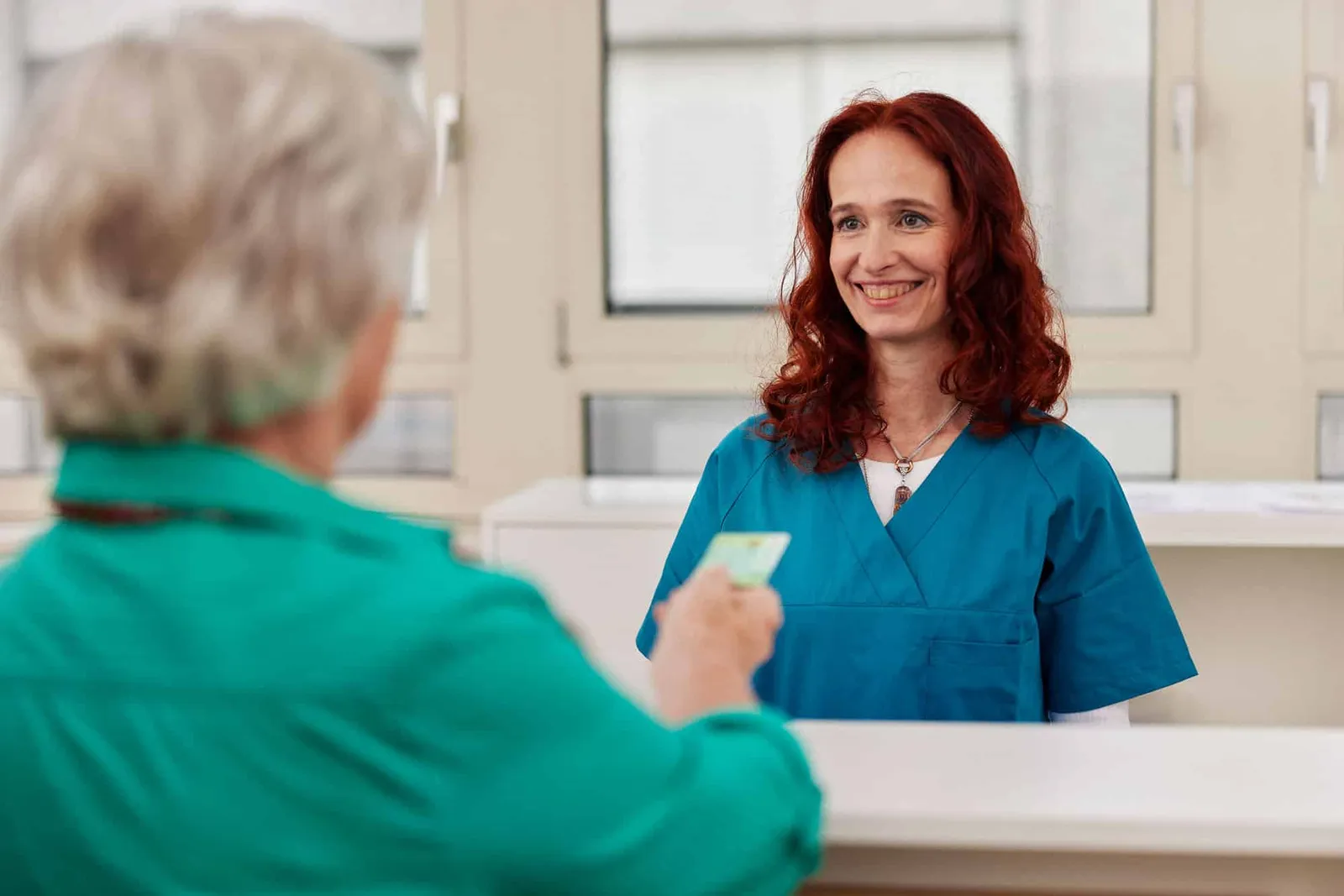 Patientin übergibt am Empfang ihre e-Card